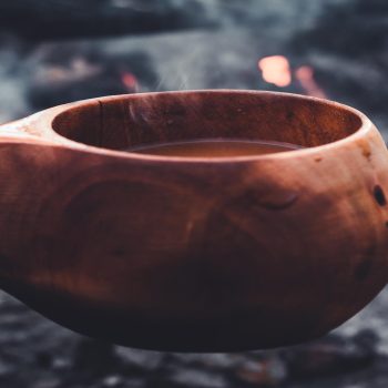 Kuksa with steaming coffee in front of campfire